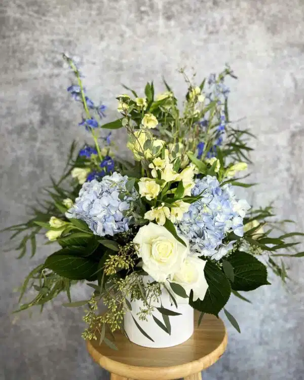 sympathy arrangement with blue hydrangeas and white roses
